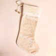 Personalised Large Starry Cream Velvet Christmas Stocking against a a beige surface