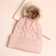 Pink Cable Knit Pom Pom Bobble Hat on Neutral Surface