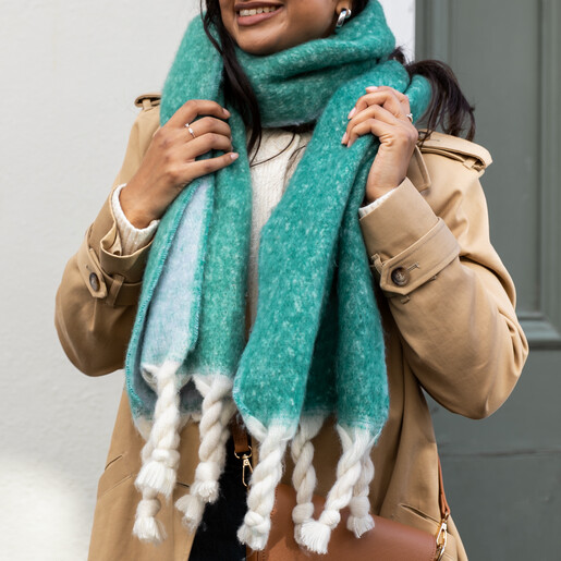 Turquiose Two Tone Winter Scarf A Model Wearing a Green and Blue Tonal Winter Scarf with Chunky White Braided Tassels Styled With a Tan Trench Coat