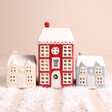 A sweet christmas house set up with one tall house and two square houses.