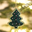 Close up of Christmas Tree Beaded Hanging Decoration hanging on a tree with warm fairy lights in background