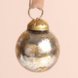 Close up of Silver and Gold Mini Bauble on a beige background