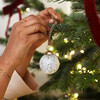 Christmas Campaign Shot White Mottled Textured Bauble being hung on Christmas Tree 