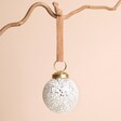 White Mottled Textured Bauble on a beige background