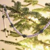 A Wooden Beaded Garland Featuring Natural and Green Wood Beads Draped Across Christmas Tree Branches