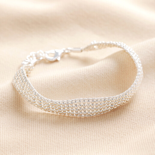Beaded Woven Cord Bracelet in Silver Beaded Woven Cord Bracelet in Silver on a Beige Background.