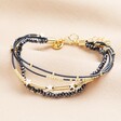 An attached, three strand bracelet in navy with gold star charms and gold beading.