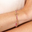 A dual layered bracelet with a gold beaded layer and a pink and white agate beaded layer with a doodle style heart charm close up on a models wrist