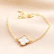 Shell Flower Charm Bracelet in Gold on a Beige Background.