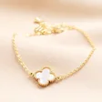 Shell Flower Charm Bracelet in Gold on a Beige Background.