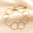 Stainless Steel Hoop Wrap on a Beige Background. Bracelet in Gold