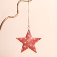 A metal red star hanging decoration with snowflake pattern