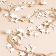 White Wooden Stars LED String Lights on a Beige Background.