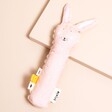 Light pink Trixie Bunny Baby Squeaker Toy with floppy ears on a beige background