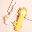 Pink Bunny and Yellow Lion squeaker toys on a beige background