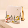 Floral Bee Compact Mirror Stood Against Beige Surface