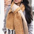 A Brunette Model Wearing a Camel Dual Toned Knitted Blanket Scarf Tied into a Knot