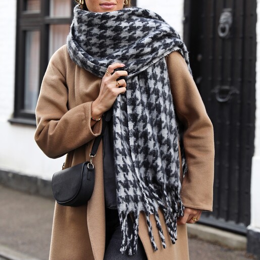 Charcoal Houndstooth Winter Scarf A Model Wearing a Grey Checked Knitted Blanket Scarf Thrown Over One Shoulder With a Tan Coat