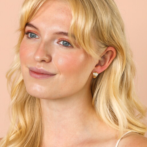 Clam Huggie Hoop Earrings in Gold on a neutral background