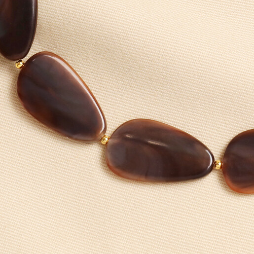 Close up of swirled brown resin pebble beads and gold accent beads