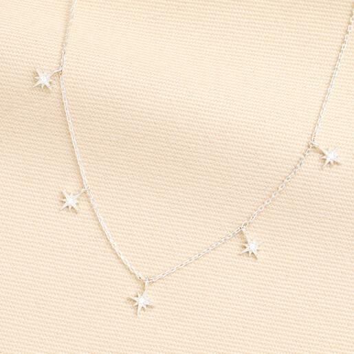 Silver chain necklace with crystal-embellished star charms on a neutral woven background.