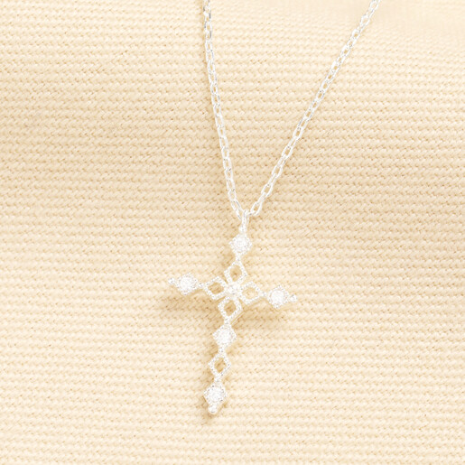 Silver chain necklace with a crystal cross pendant on a beige background
