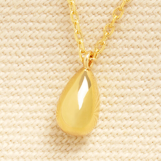 Close up of gold teardrop charm suspended on gold chain