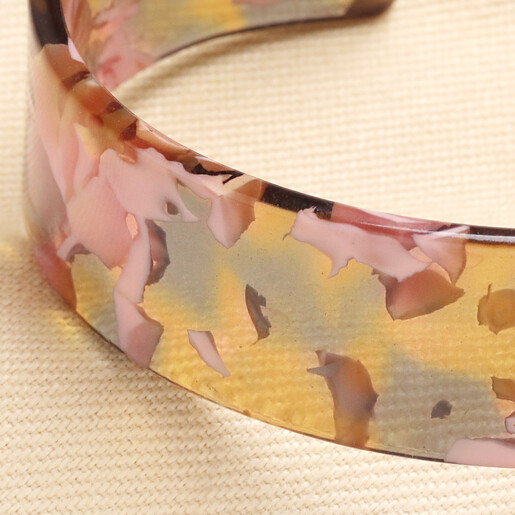 Close up view of smooth pink and amber pattern on resin cuff bracelet