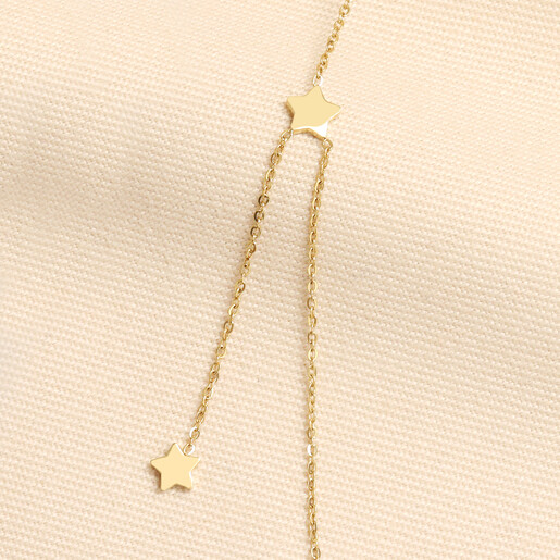 Close up of gold star charm and drop detail on fine chain necklace