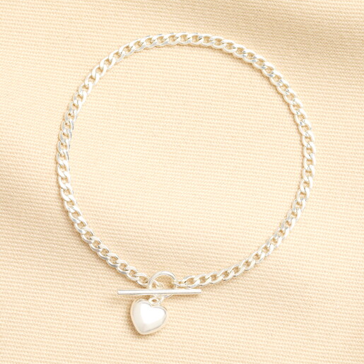Silver small T-bar heart charm curb chain bracelet laid on fabric.