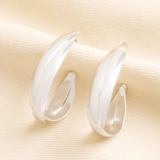 Pair of organic interlocking hoop earrings in silver on textured cream fabric