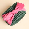 Top-down view of the large knotted pink velvet bow on the green cosmetic case