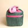 Side view of the structured green ribbed velvet makeup bag with pink zipper