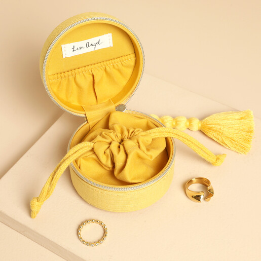 Open yellow jewellery case showing internal drawstring pouch, lid pocket, and gold rings