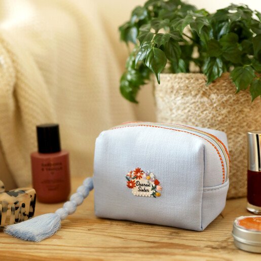 Small light blue embroidered makeup bag with Dearest Sister floral motif and beaded tassel