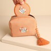 Matching Darling Daughter compact mirror being placed into the open orange makeup bag