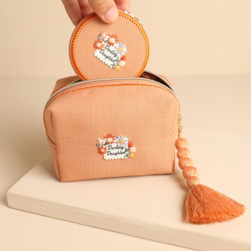 Matching Darling Daughter compact mirror being placed into the open orange makeup bag
