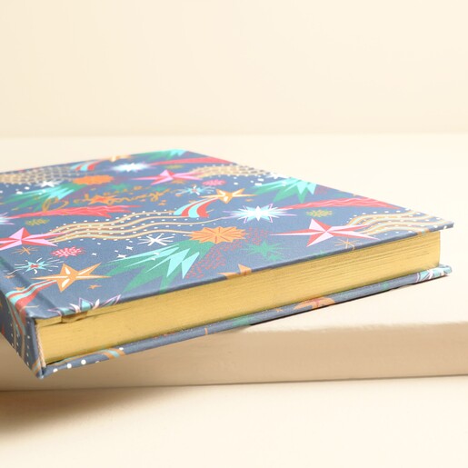 Angled view of navy celestial notebook showing lustrous gilded gold page edges