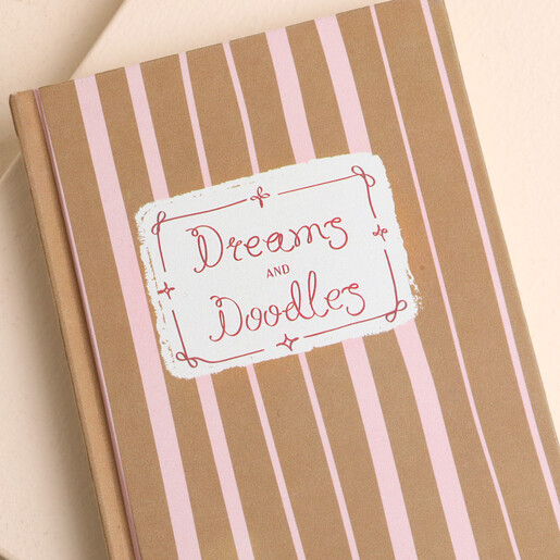 Close up of Dreams and Doodles label on pink striped notebook