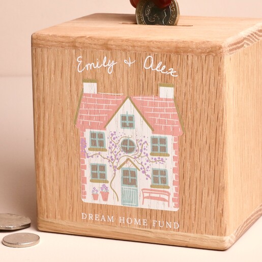 Close-up of personalised wooden money box with printed cottage and couple names