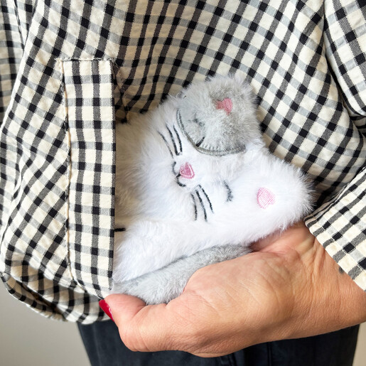 Fluffy cat hand warmer being slipped into a jacket pocket