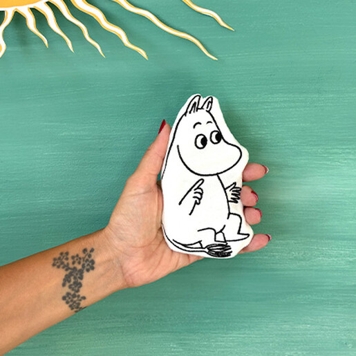 Person holding a white fabric Moomin shaped hand warmer with black line details.