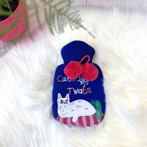 Blue embroidered Cats Before Twats mini hot water bottle on a white fluffy rug