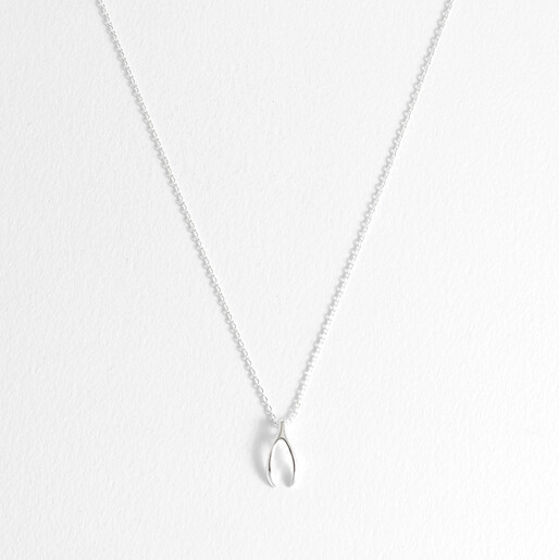 Delicate Estella Bartlett silver plated wishbone charm necklace on a plain white backdrop