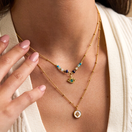Model wearing the Estella Bartlett evil eye beaded necklace layered with gold jewellery