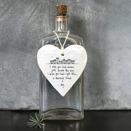 East of India white ceramic heart hanging decoration displayed on a vintage glass bottle.