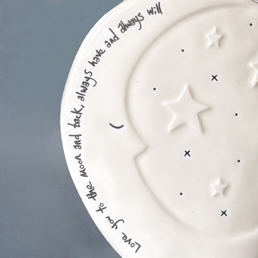 Close-up of white ceramic vase showing debossed sentiment and raised stars