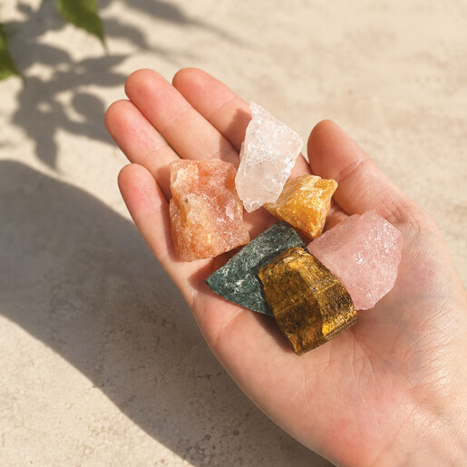 Hand holding six colourful raw healing crystals from the gift set