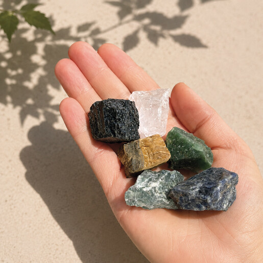Hand holding six raw colourful crystals from the set