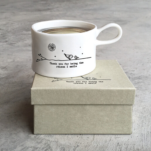East of India white ceramic cup tealight holder sitting on illustrated gift box